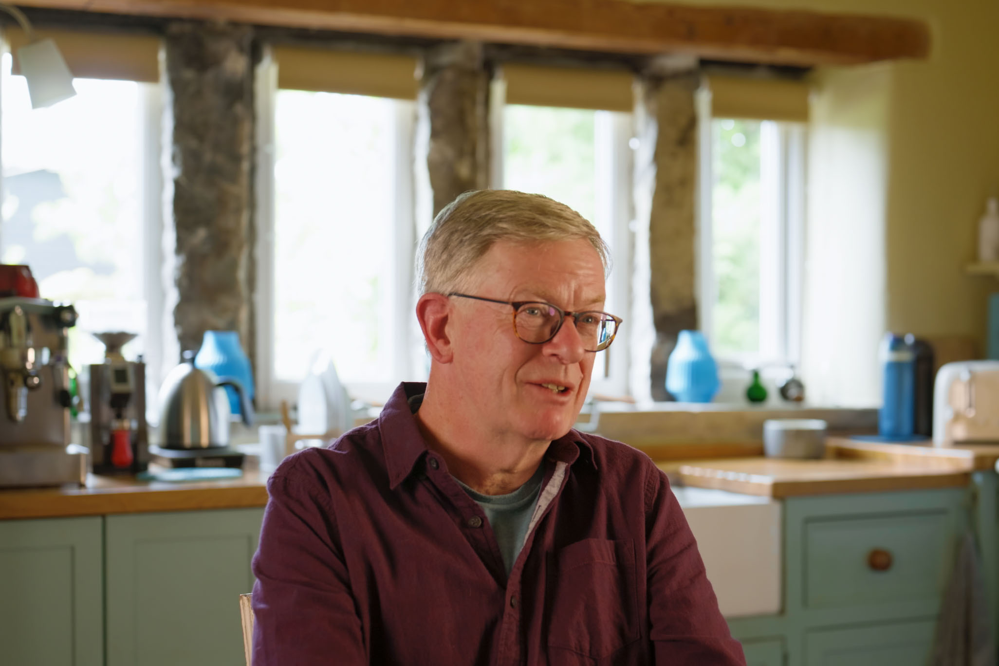Tony sitting in his traditional stone-mullioned cottage kitchen in the Pennines with a Belfast sink and oak worktop behind him.
