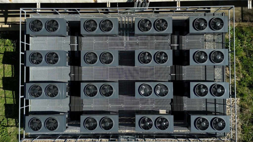 Top-down drone photograph of the complete 16-unit Ochsner commercial air source heat pump array at Todmorden Sports Centre.