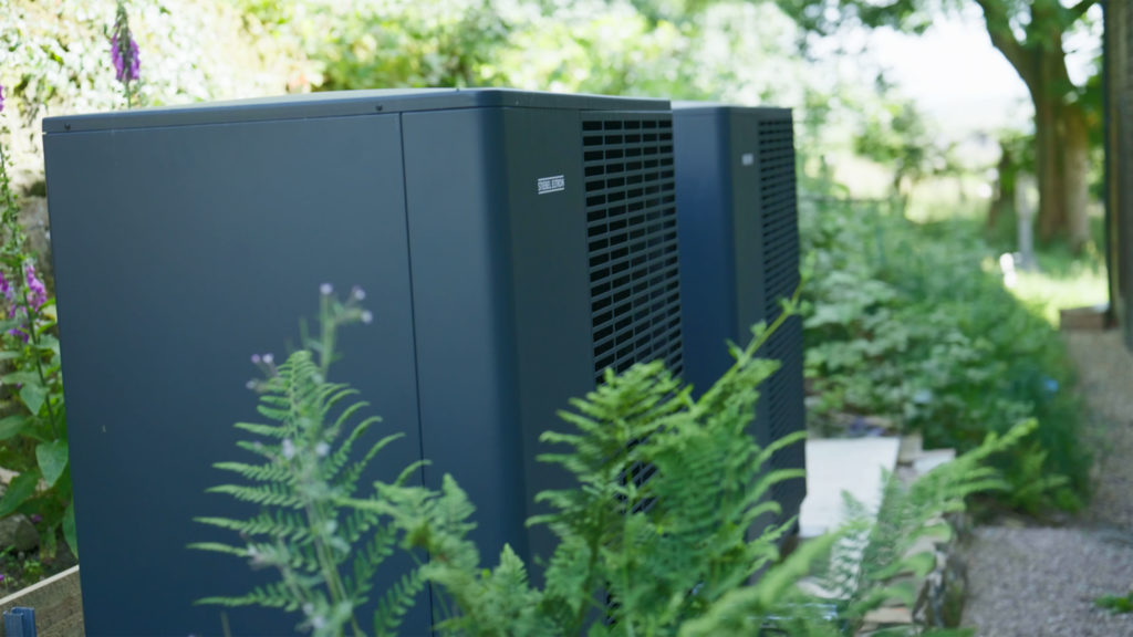 Twin grey Stiebel Eltron air source heat pumps discreetly tucked amongst greenery behind the historic Wainsgate Chapel.