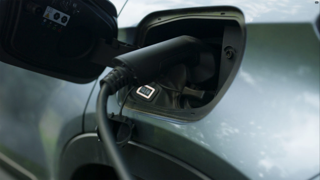 Close-up of an electric vehicle charging cable plugged into a car outside a stone home in West Yorkshire.