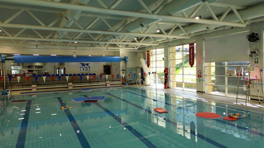 High-angle interior view looking across the main swimming pool hall inside Todmorden Sports Centre.